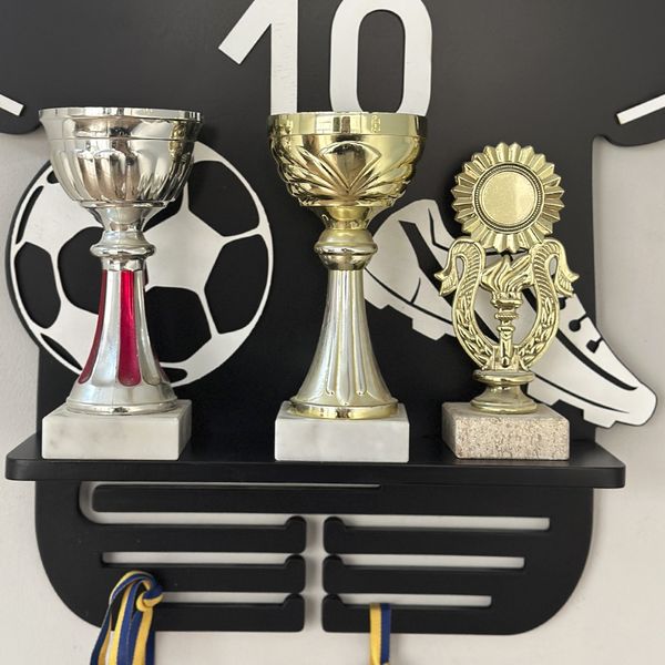 Shelf for football player's cups and medals in the form of a football uniform