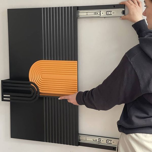 Designer wall key holder under the shield with a slider system