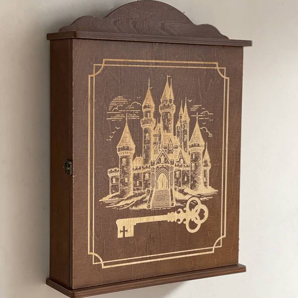 Wall mounted key holder with a door with a picture of a castle